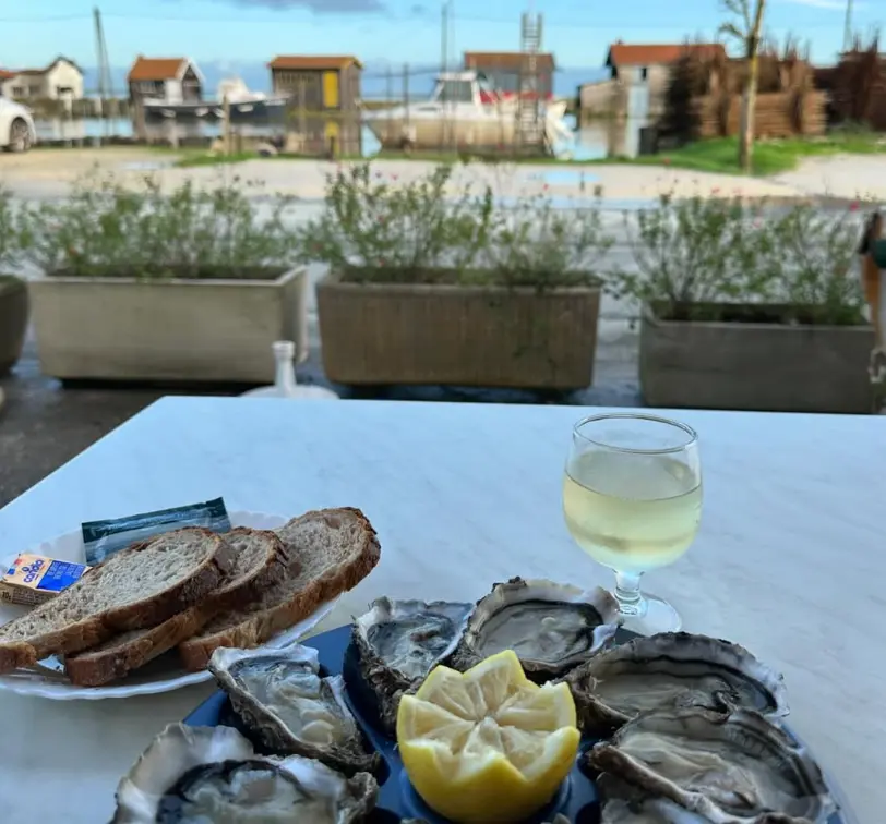 Assiette d'huîtres et verre de vin blanc face au port